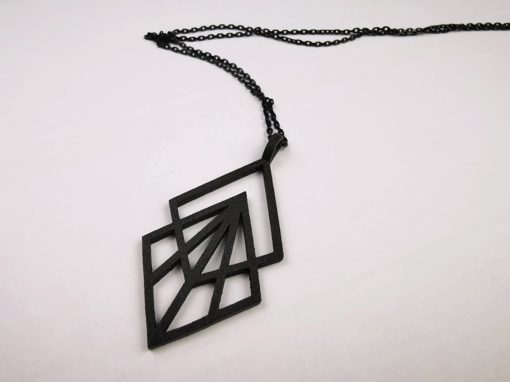 A photo of a black steel geometric jewelry piece that I created for a friend, printed and processed by Shapeways. The jewelry piece is displayed on a neutral white background.