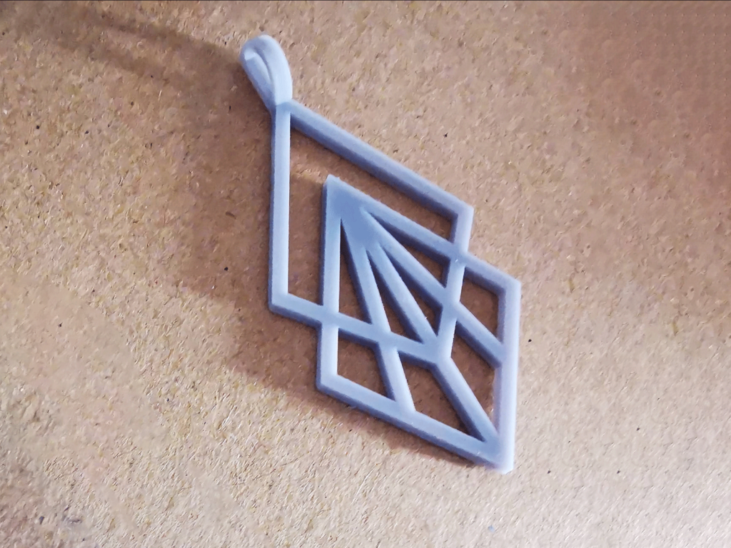 A 3D printed geometric jewelry piece on a tan background.